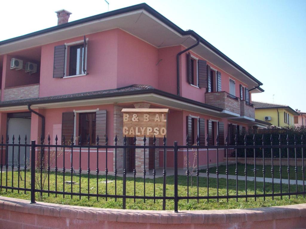 une maison rose avec une clôture devant elle dans l'établissement Al Calypso, à Curtatone