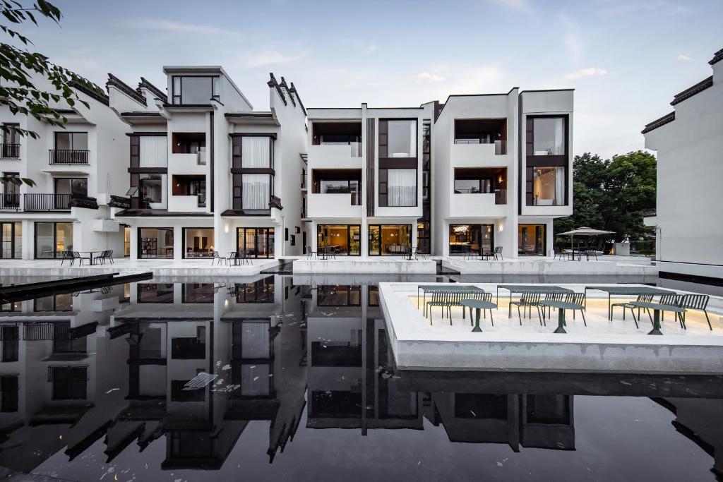 un edificio con tavoli e sedie accanto a un corpo d'acqua di 乌镇乌外坞酒店 a Tongxiang