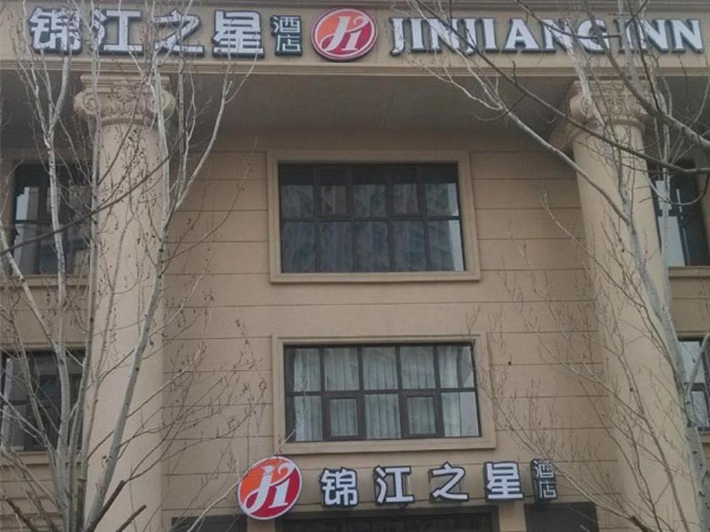 un edificio con letreros en el costado en Jinjiang Inn Shenyang North Railway Station Huigong Square, en Shenyang