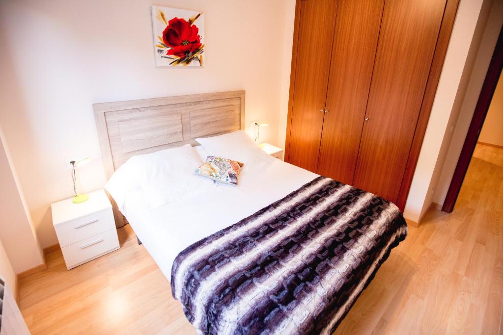 1 dormitorio con cama blanca y manta a rayas en Apartaments Ashome en Canillo