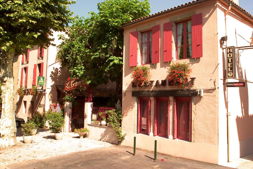 un edificio con persianas rojas y flores en las ventanas en Hôtel Le Commerce en Mirepoix