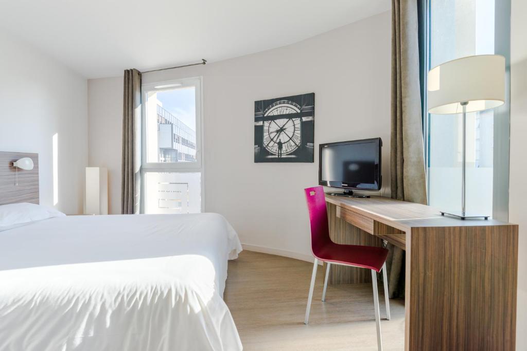 a bedroom with a bed and a desk with a television at Appart’hôtel Hevea in Valence