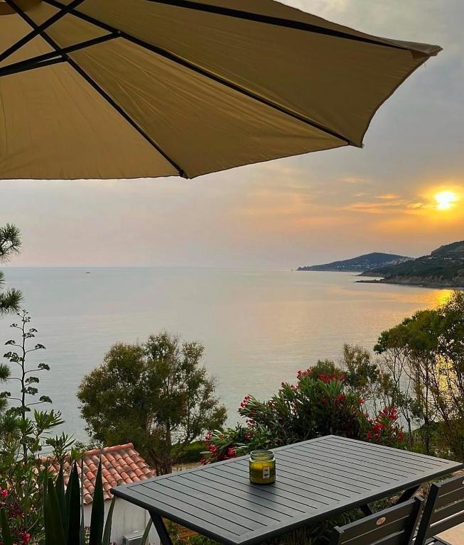 - une table avec un parasol et une vue sur l'eau dans l'établissement Appartement bord de mer 2 personnes, à Sagone