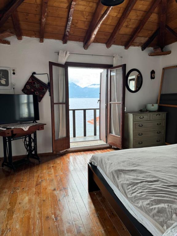 ein Schlafzimmer mit einem Bett und einem großen Fenster in der Unterkunft Cottage by the Sea in Vathy Methana in Megalochori