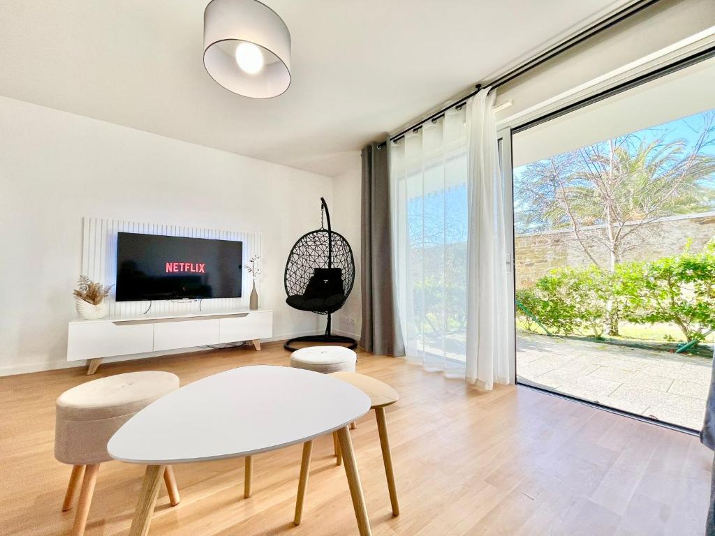 a living room with a table and chairs and a tv at ParcAppart 5 - Terrasse - Parking - Netflix in Lanester