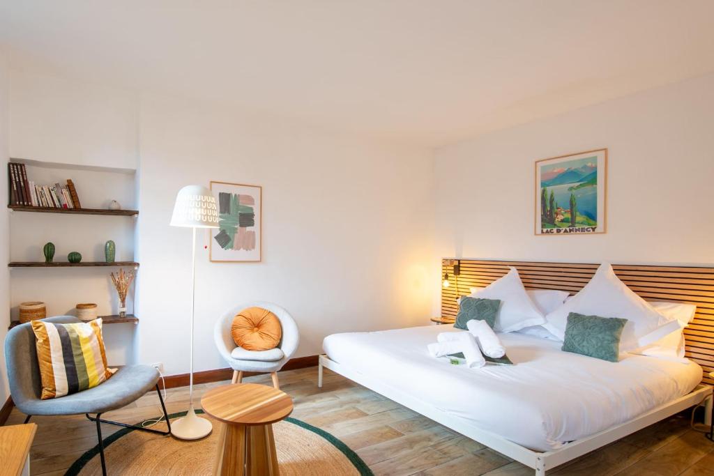 une chambre avec un lit blanc et une chaise dans l'établissement Le Bohème, à Annecy