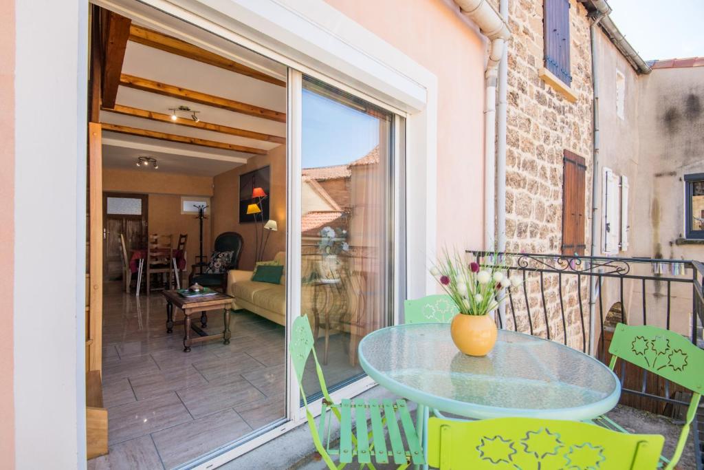 d'une terrasse avec une table en verre et des chaises sur un balcon. dans l'établissement Maison le vieux Creissels 4pers balcon parking gratuit, à Creissels