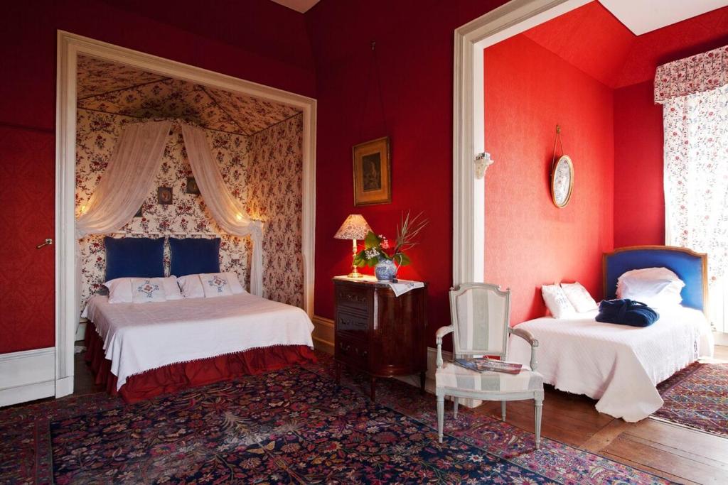 Cette chambre rouge comprend deux lits et une télévision. dans l'établissement Chateau de Sannat, à Saint-Junien-les-Combes