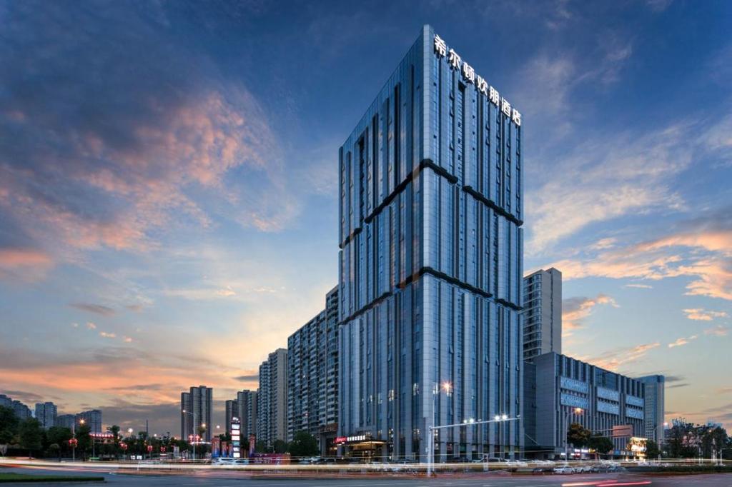 Un alto edificio de cristal frente a una ciudad. en Hampton by Hilton Changsha South Railway Station West Square, en Changsha
