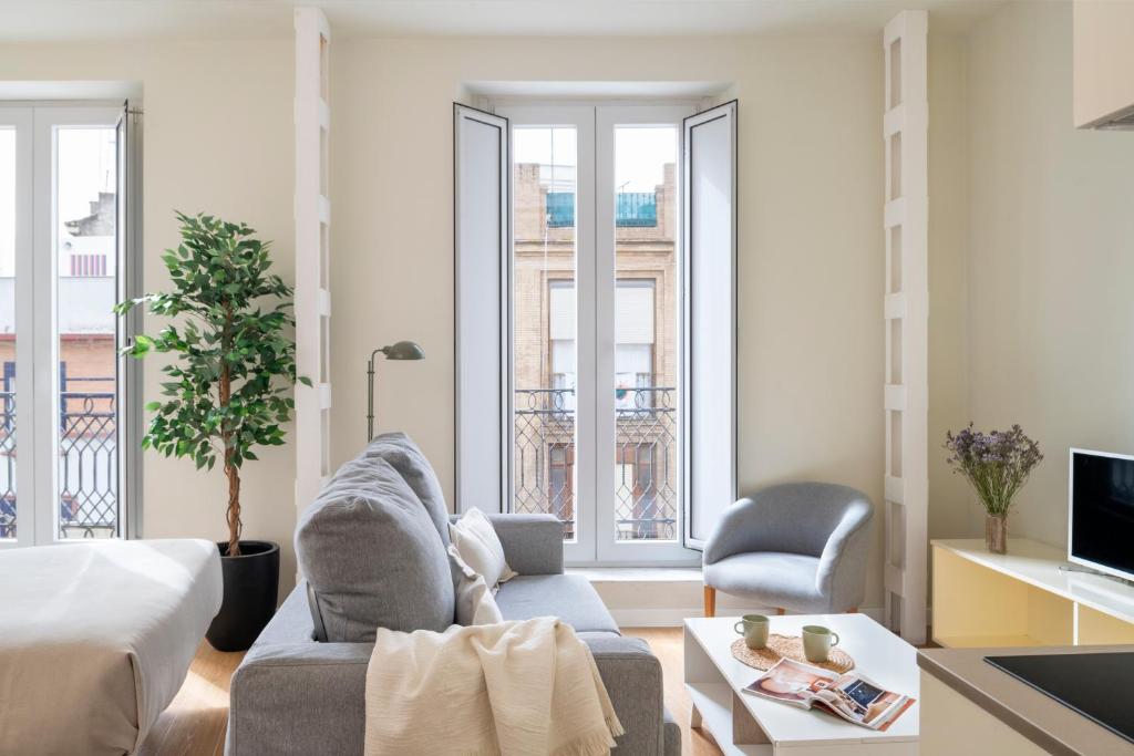 een woonkamer met een bed, een bank en stoelen bij Ópera Apartments Alameda in Sevilla