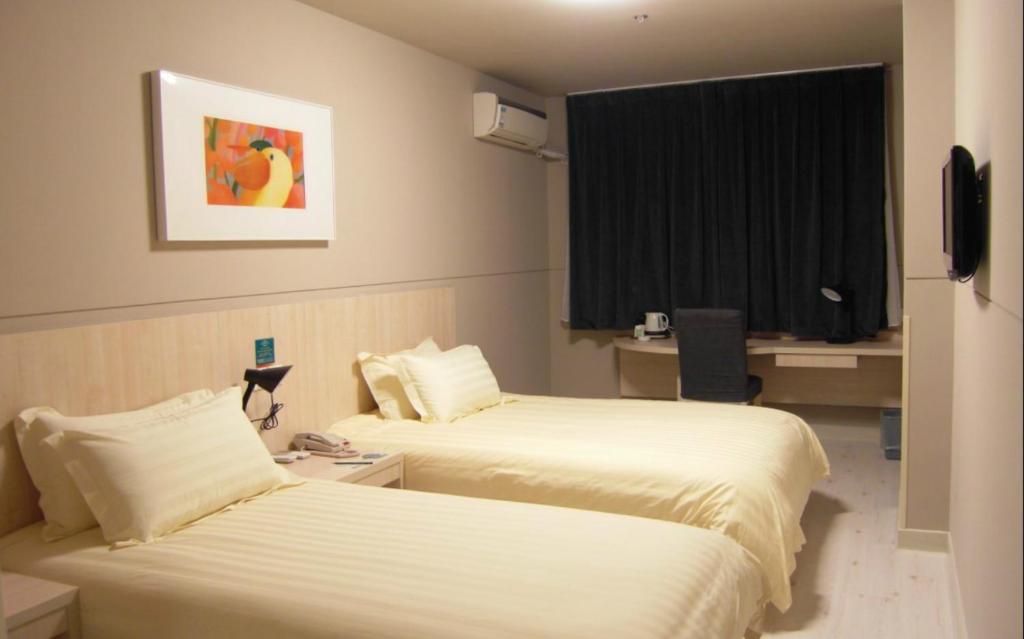 a hotel room with two beds and a window at Jinjiang Inn Yanji Railway Station Municipal Government in Yanji