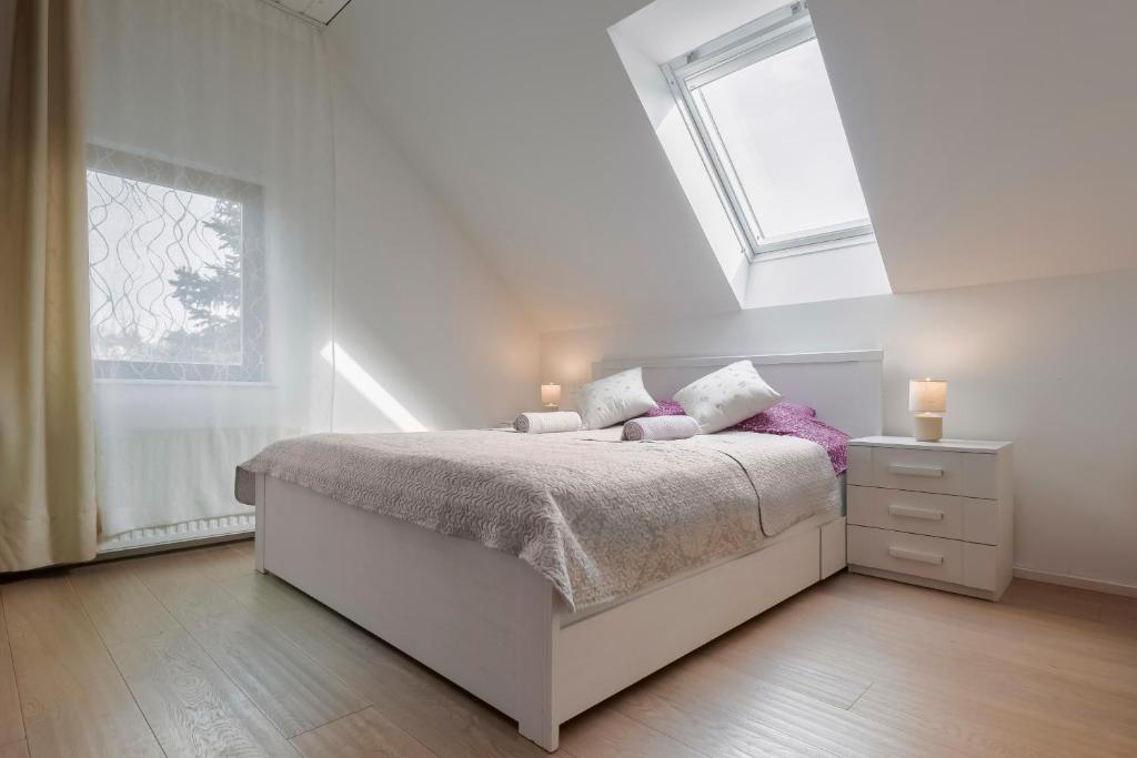 a white bedroom with a bed and a window at Guest House KRISTI in Tuchoměřice