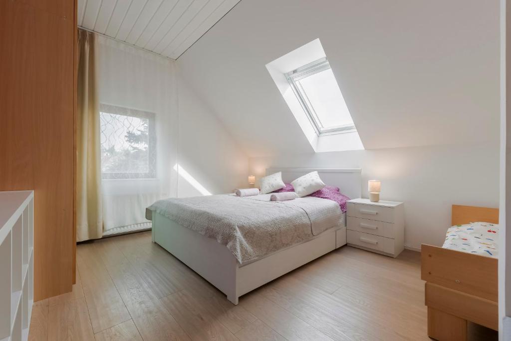 a white bedroom with a bed and a window at Guest House KRISTI in Tuchoměřice
