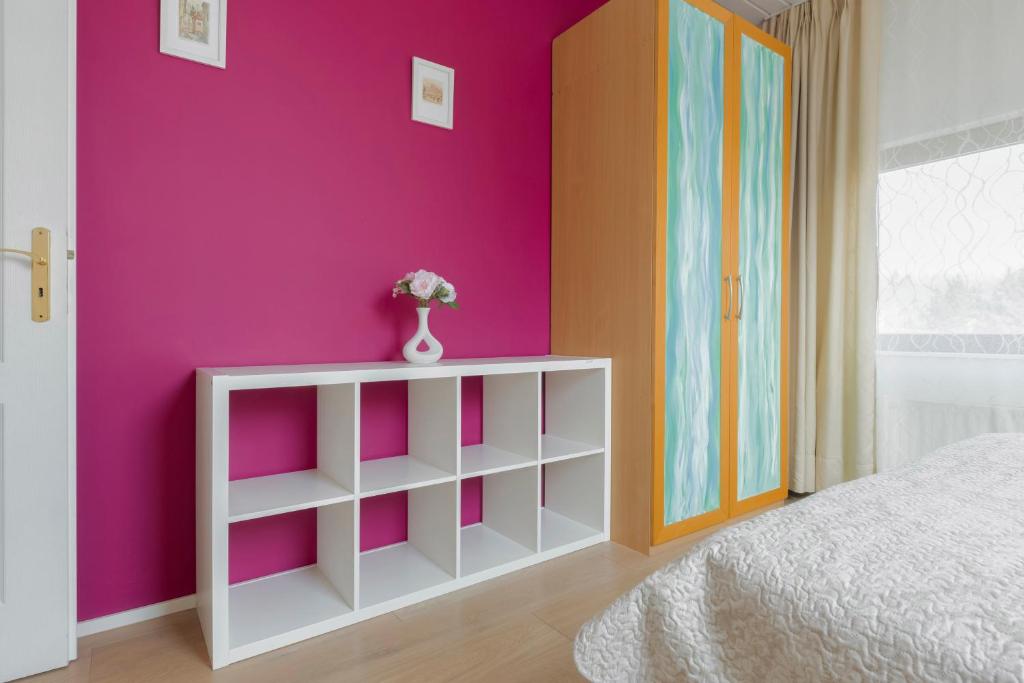 a bedroom with a pink wall and a white cabinet at Guest House KRISTI in Tuchoměřice