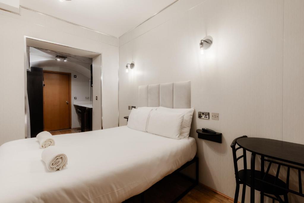 a bedroom with a large white bed and a table at Britannia Hyde Park Hotel by PLI in London