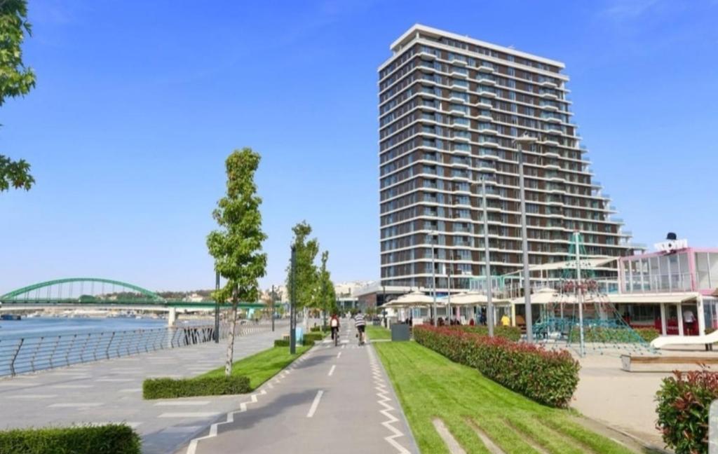 a tall building next to a walkway next to a building at Beograd na vodi - Belgrade Waterfront Iris Apartment in Belgrade