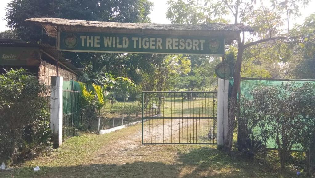un cancello con un cartello che legge il resort delle tigri selvatiche di The Wild Tiger Resort a Jyoti Gaon
