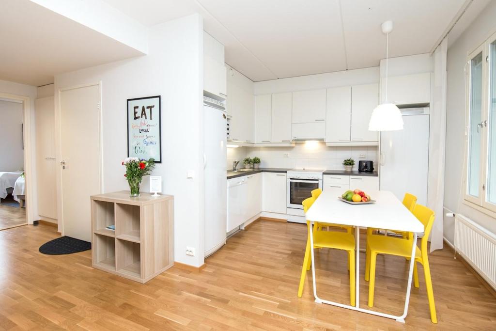a kitchen and dining room with a table and yellow chairs at Kotimaailma Two bedroom apartment with private sauna in Vaasa