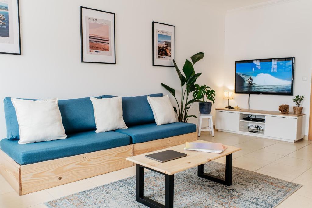 a living room with a blue couch and a coffee table at Green House in Baleal