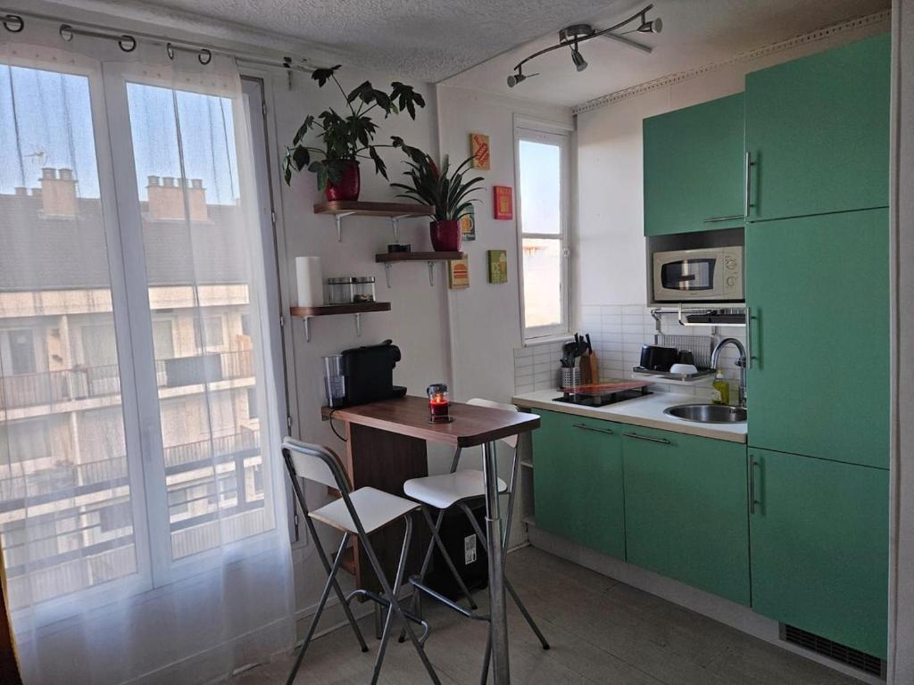 une cuisine avec des armoires vertes, une table et des chaises dans l'établissement Studio centre ville-Proche Paris, à Villejuif
