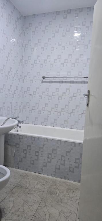 a bathroom with a tub and a toilet and a sink at Hungwe Apartment in Harare