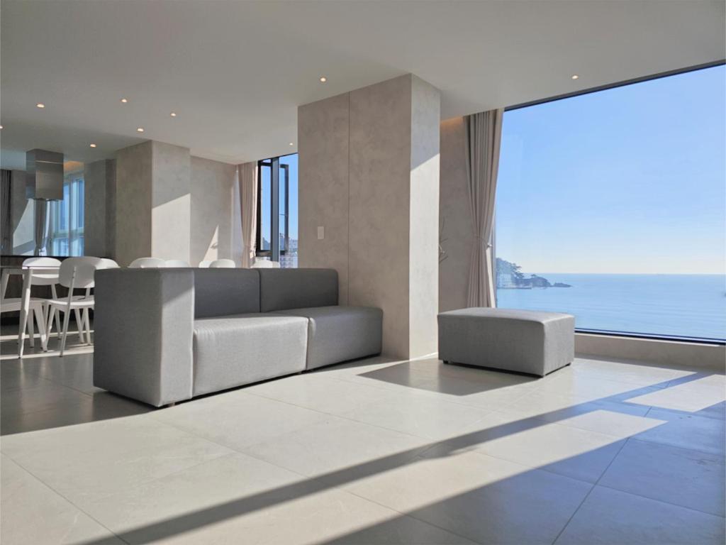 a living room with a couch and a view of the ocean at 펜톤나인 해변열차 송정2호점 in Busan