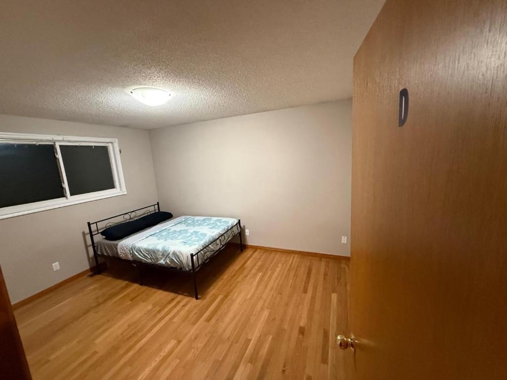 a bedroom with a bed in a room with a wooden floor at Smart Budget Friendly Room-Near Airport, Groceries,College in Kitchener