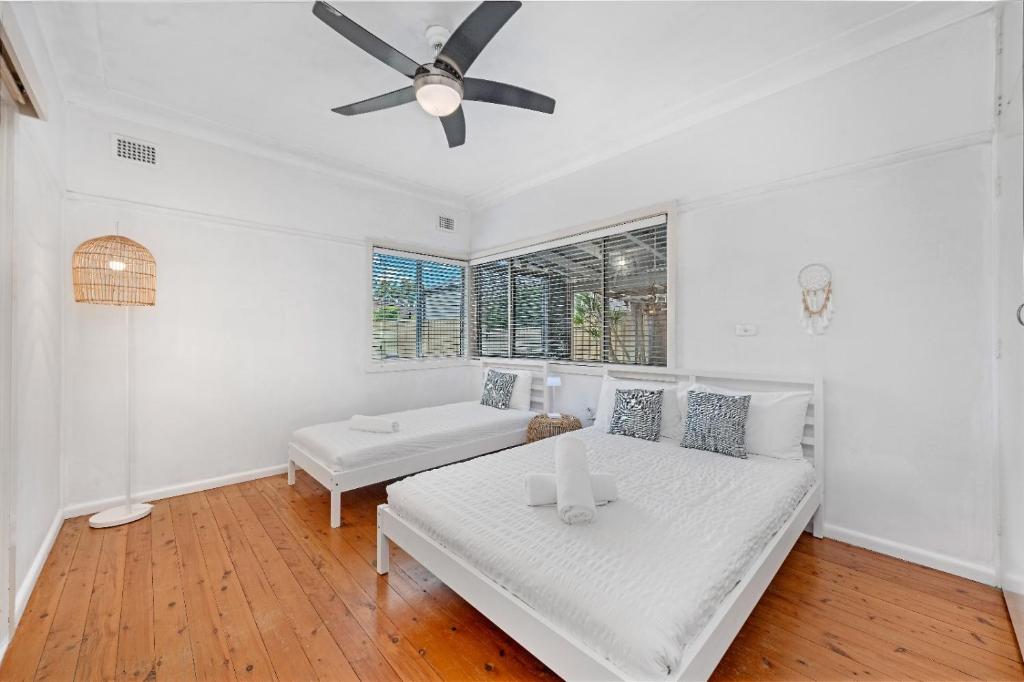 a white room with a bed and a ceiling fan at Sans Souci 4-Bedroom Home Near Beach in Sydney