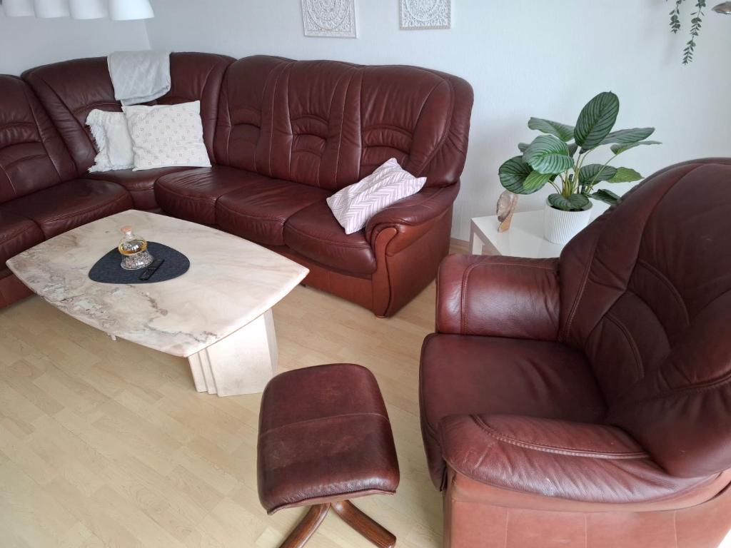 a living room with a brown leather couch and a table at Ferienwohnung Schöne Zeit in Nordenham