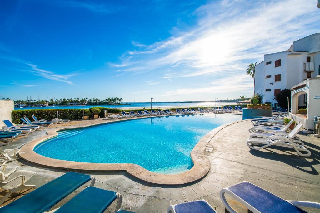 a swimming pool with lounge chairs and the ocean at Ideal Property Mallorca - Dali 127 in Port d'Alcudia
