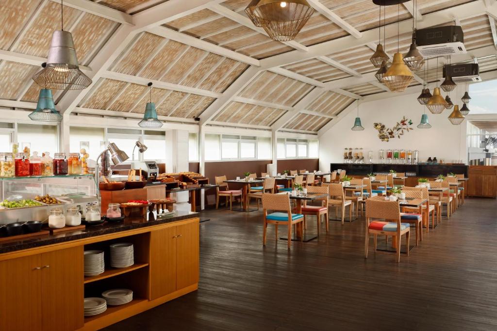 a large dining room with tables and chairs at Aston Canggu Beach Resort in Canggu