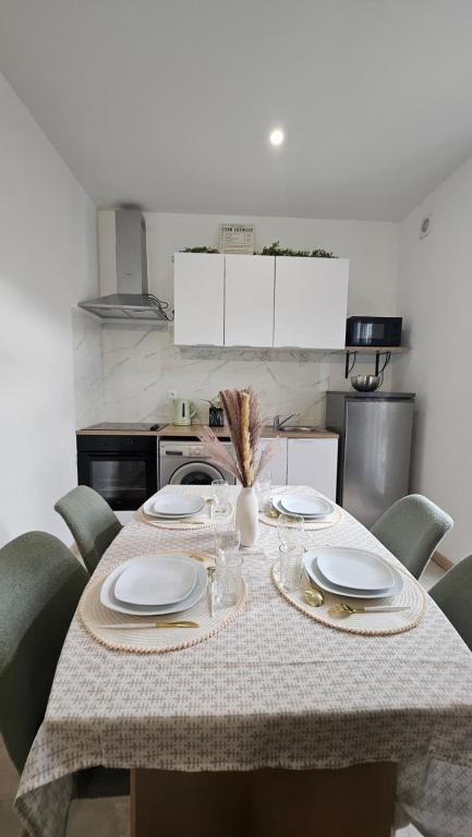 - une table avec des chaises et des assiettes dans la cuisine dans l'établissement Maison La Valenciennoise, à Valenciennes
