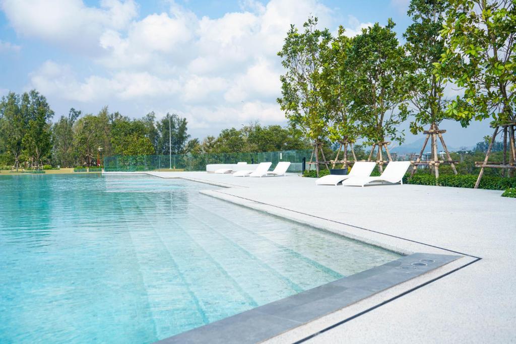 a swimming pool with white chairs and water at Laguna Beachside residences apartamens, walking distance to the sea in Bang Tao Beach