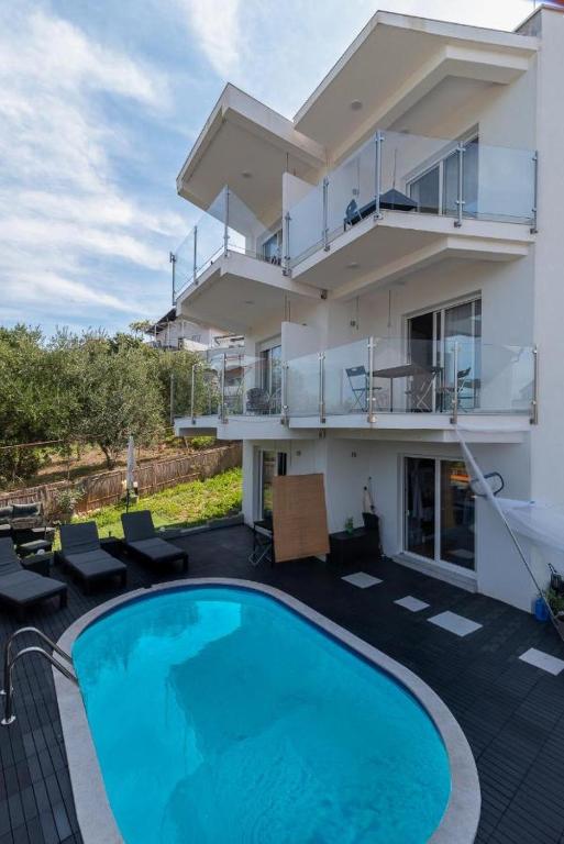 a building with a swimming pool in front of a house at Apartmani Marko in Trogir