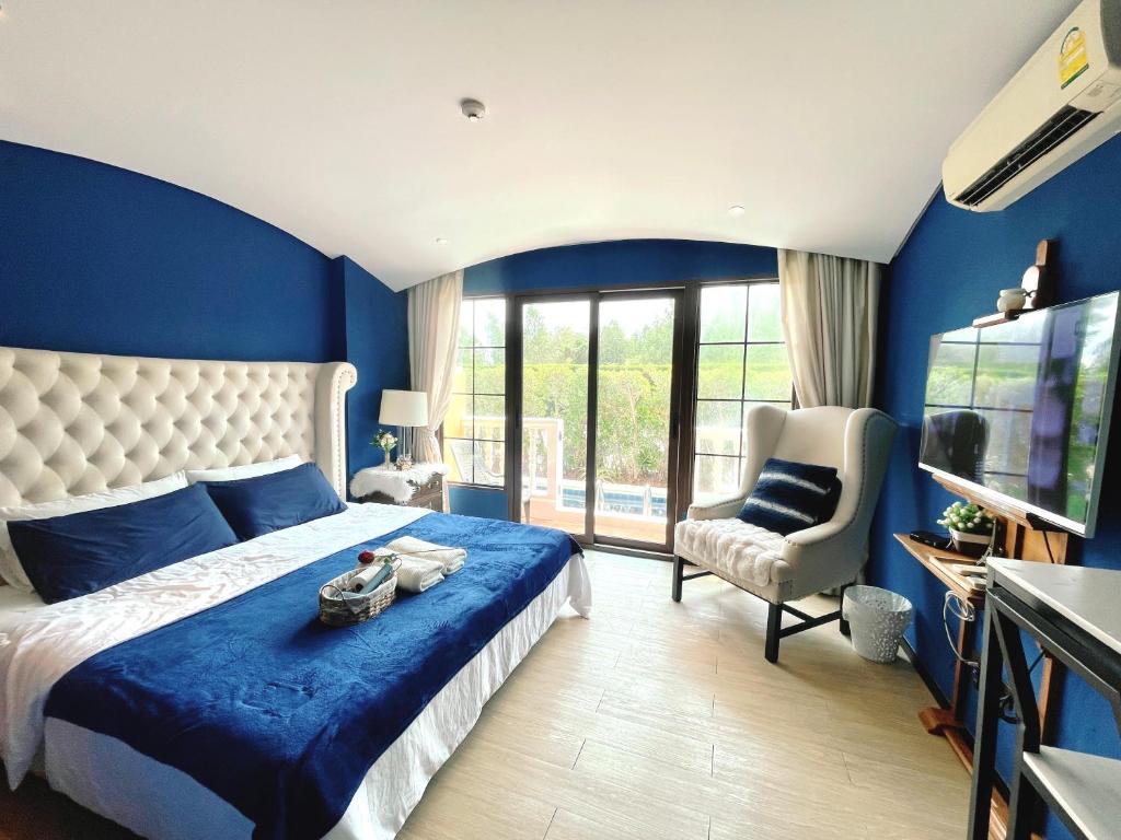 sypialnia z niebieskimi ścianami, łóżkiem i krzesłem w obiekcie Venetian Signature Condo Pattaya w mieście Jomtien Beach