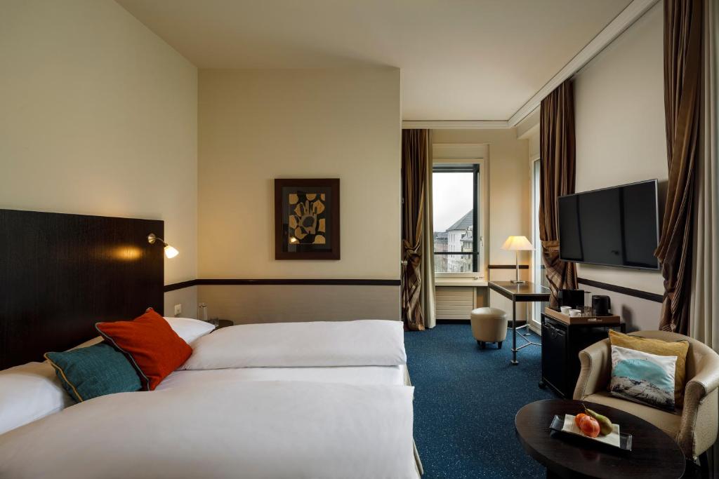 a hotel room with two beds and a television at Opera Hotel Zürich in Zürich