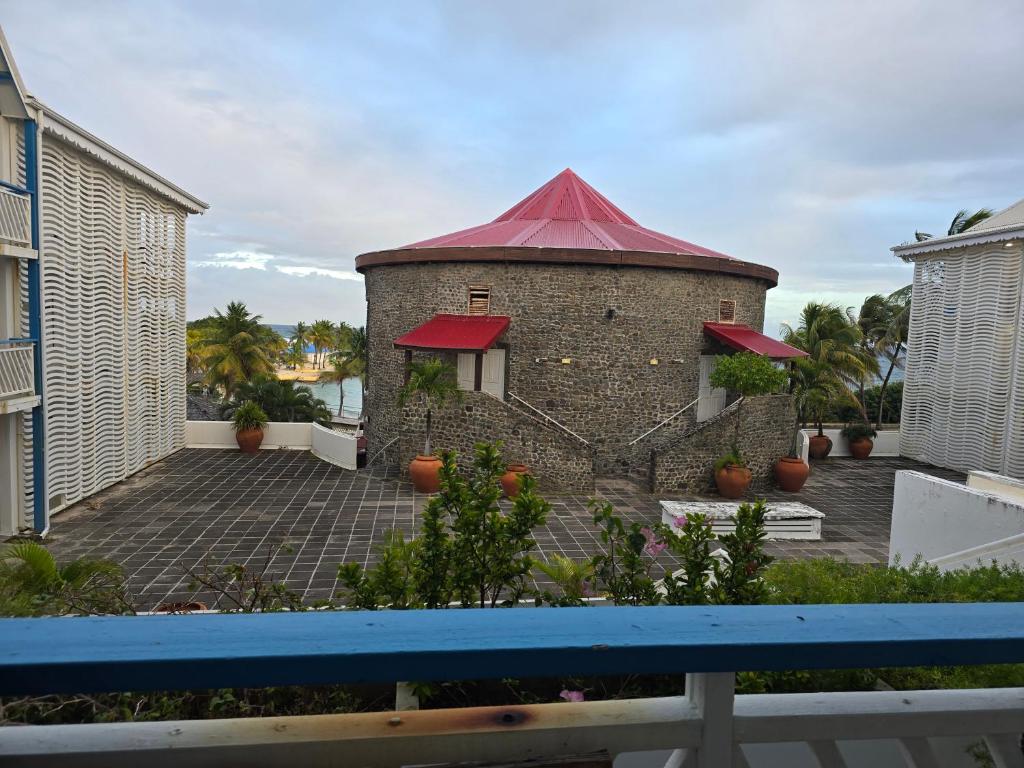 een bakstenen gebouw met een rood dak op een terras bij Studio Lucie à MANGANAO in Saint-François