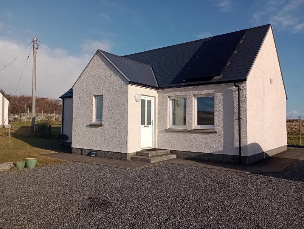 a house with a solar panel on top of it at Crossroads Cottage in Sollas