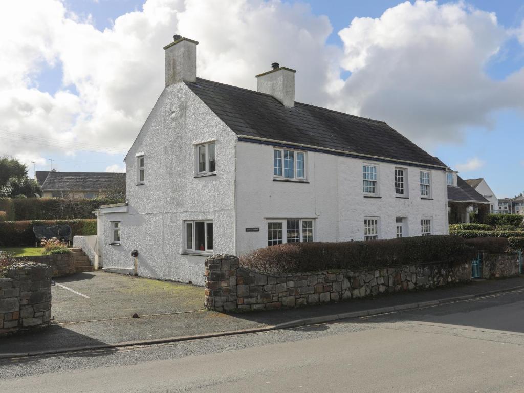 a white house with a black roof on a street at Glan Y Don Bach in Abersoch