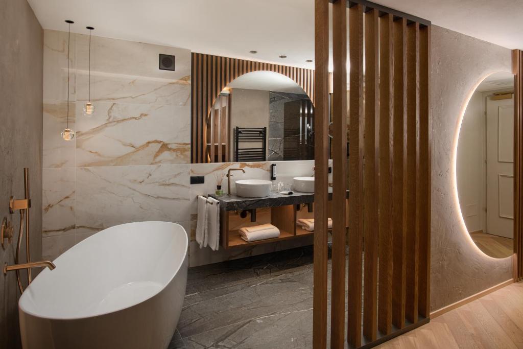 a bathroom with a tub and a sink and a mirror at Majestic - Unique Spa Resort in Brunico