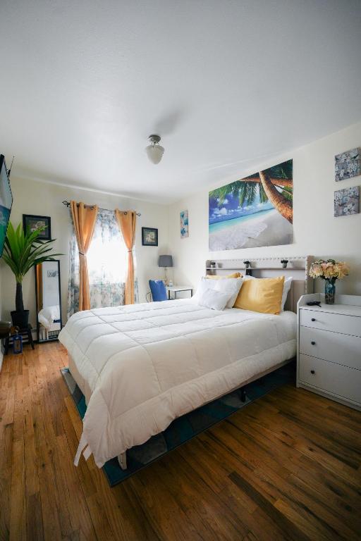 a large white bed in a bedroom with wooden floors at Chekells Cozy stay close to everything Free WIFI in Brooklyn