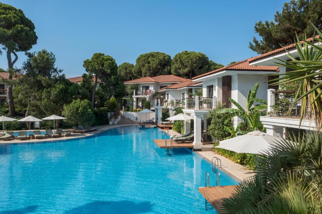 a swimming pool with chairs and umbrellas at a resort at Ela Excellence Resort Belek in Belek