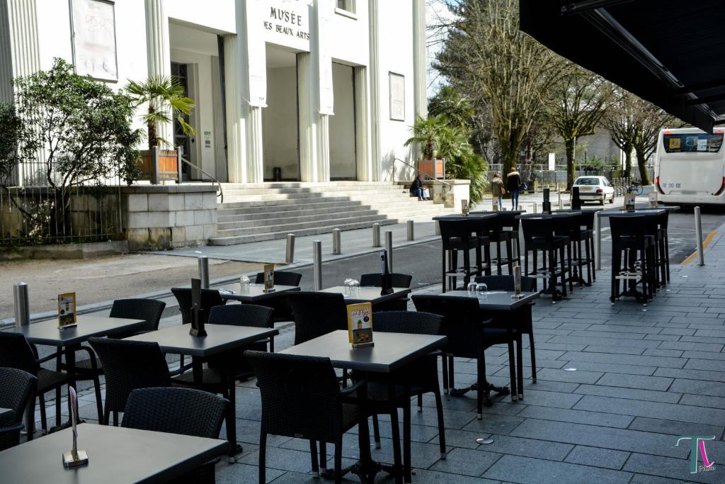 une rangée de tables et de chaises devant un bâtiment dans l'établissement Le Matisse Pau Centre, à Pau