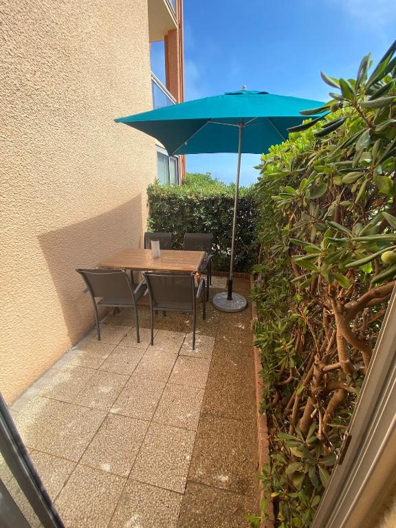 une table et des chaises avec un parapluie bleu dans l'établissement Cap de Mer Appart-4 pers, front de mer terrasse, au Barcarès