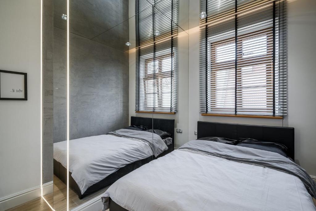 a bedroom with two beds and two windows at Rynek 2B - Old Town in Wrocław