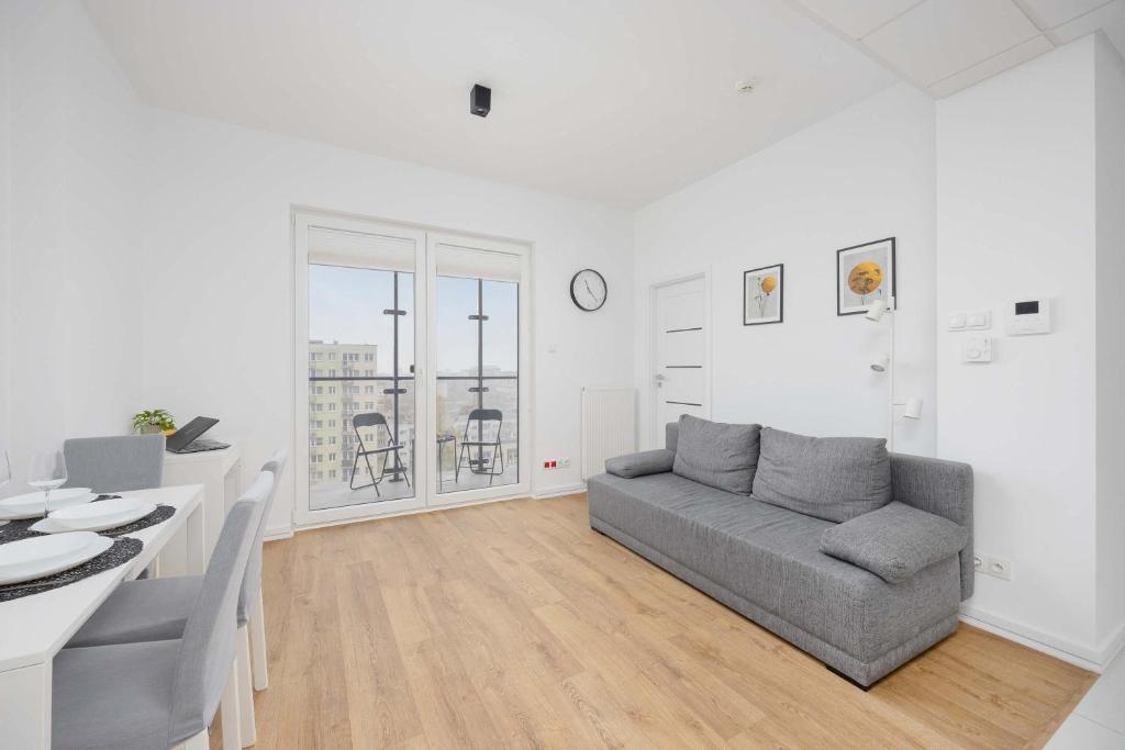 a living room with a couch and a table at Apartments Kasprzaka near Metro Płocka with AC by Noclegi Renters in Warsaw