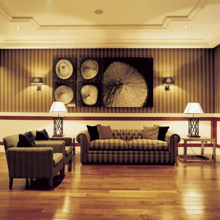 a living room with a couch and clocks on the wall at Hotel 1898 in Barcelona