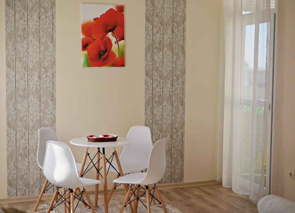 a dining room with a table and white chairs at Pipacs Apartman in Makó