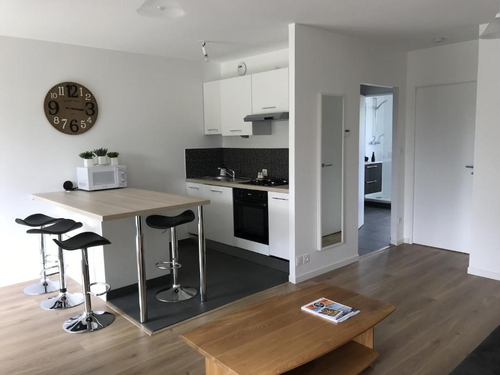 une cuisine avec une table, des tabourets et un réveil dans l'établissement VANNES Le PORT RCL, à Vannes