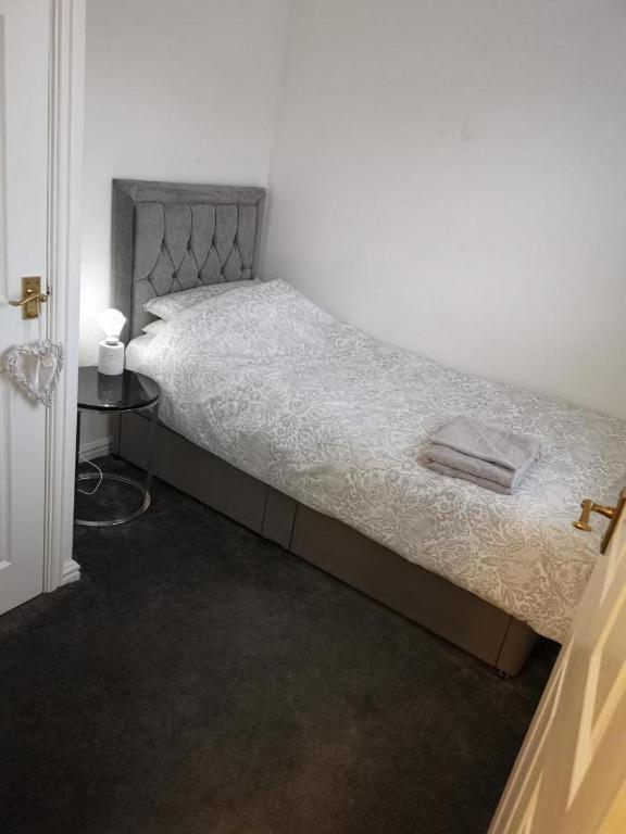 a bed in a white room with a night stand at Garden view Cosy Single Room in Derby
